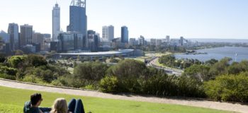 Un couple allongé sur l'herbe oberve le paysage urbain en Australie