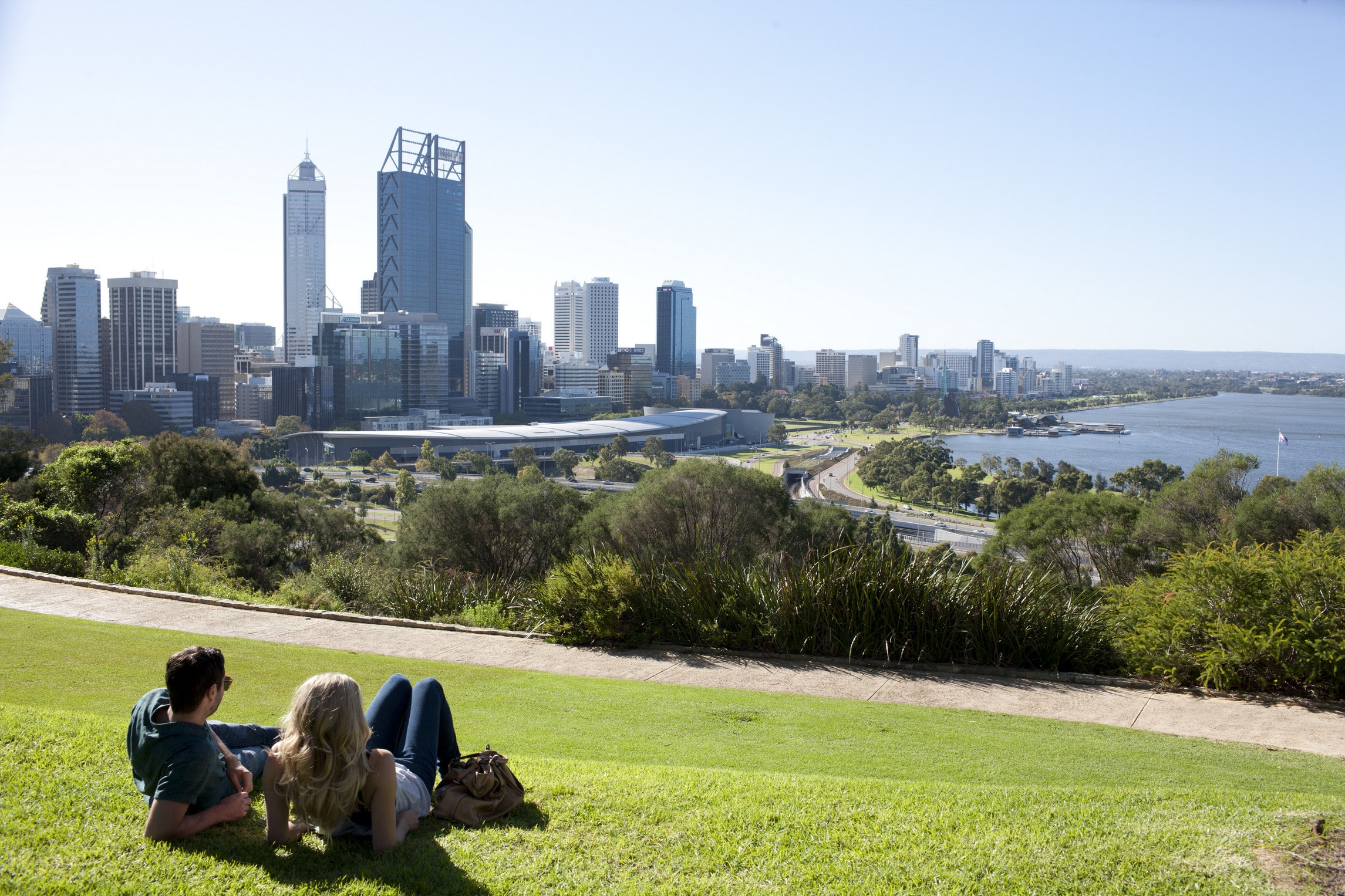 Un couple allongé sur l'herbe oberve le paysage urbain en Australie